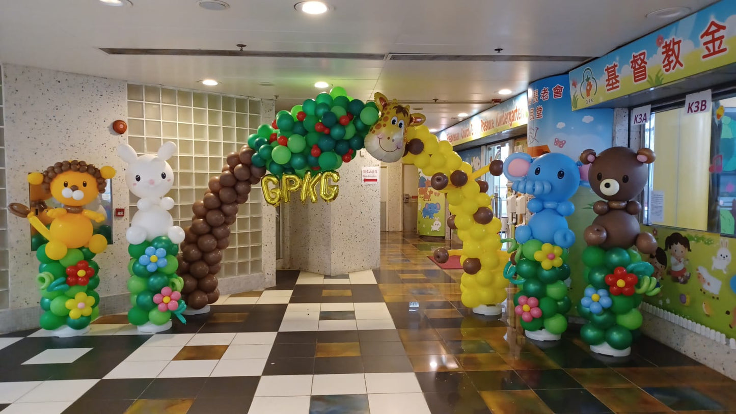 叢林/森林野生動物主題嘅氣球拱門,用綠色同啡色氣球砌成樹木,周圍有獅子、馬騮等動物造型氣球,適合學校活動或主題派對